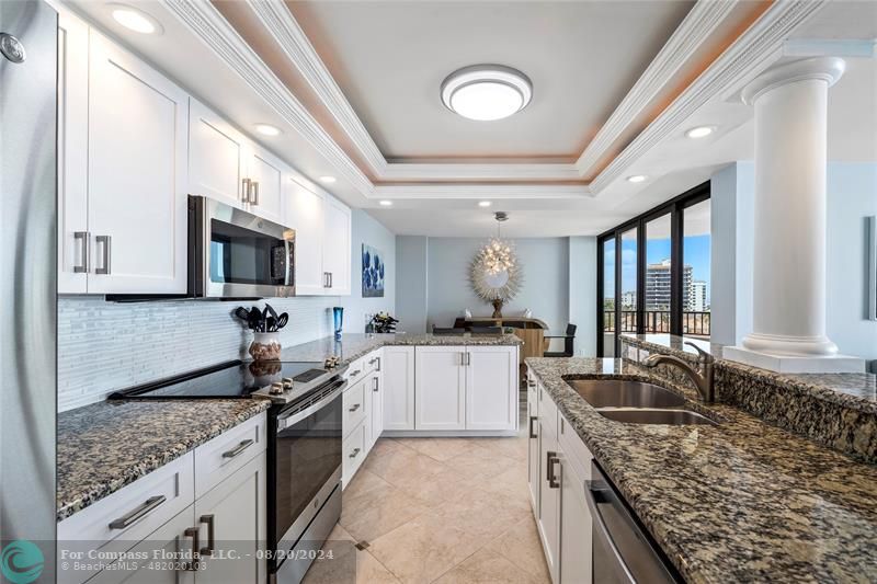 600 Ocean Drive, Unit 8D Juno Beach, FL 33408 - Photo 11 of 37 a large kitchen with granite countertop a large counter top space a sink stainless steel appliances and cabinets