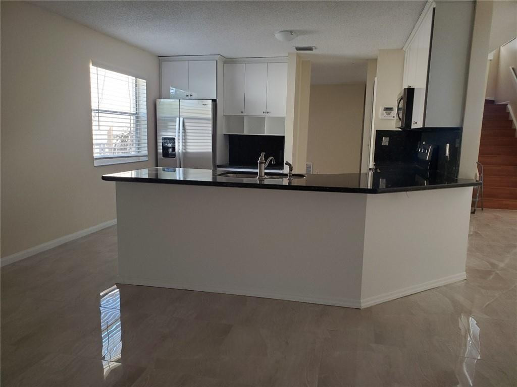 Undisclosed Address Miramar, FL 33029 - Photo 9 of 23 a kitchen with stainless steel appliances a sink a stove and a refrigerator