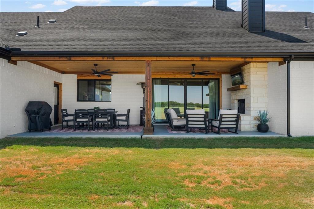 6080 Cates Rnch Drive Godley, TX 76044 - Photo 38 of 40 Covered patio featuring a ceiling fan, stone fireplace, and expansive sliding glass doors