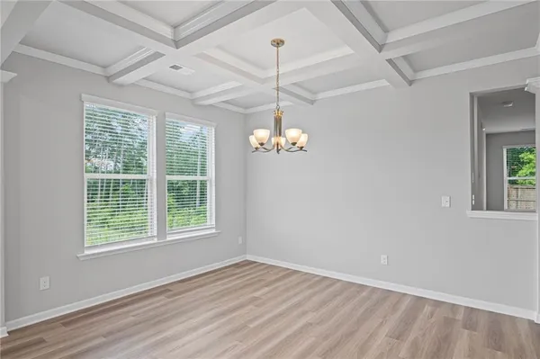 an empty room with wooden floor cabinet and windows