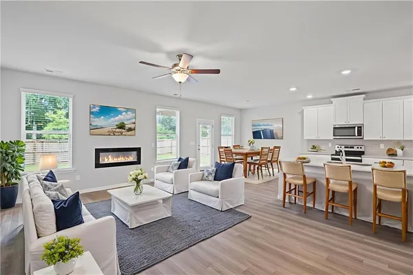 a living room with furniture kitchen view and a large window