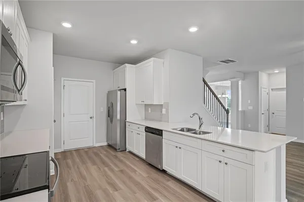 a large white kitchen with a sink and refrigerator