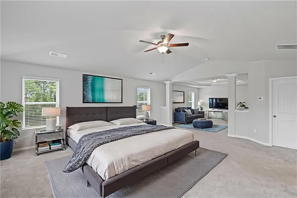 a spacious bedroom with a bed a couch and potted plant