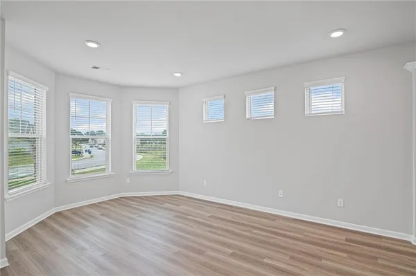 an empty room with wooden floor and windows