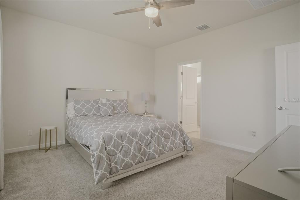 1821 Groveline Road St. Cloud, FL 34771 - Photo 24 of 36 a spacious bedroom with a bed and a chandelier fan