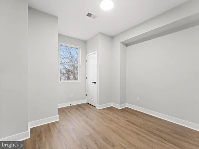 an empty room with wooden floor and window