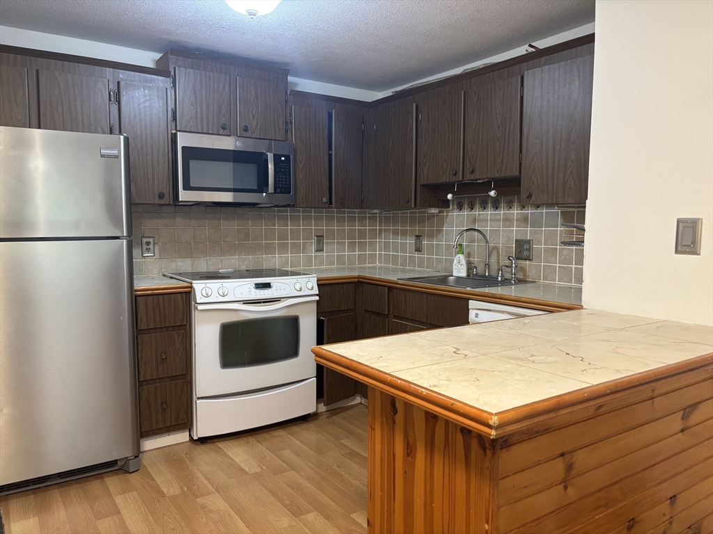 14 B Mayberry Drive, Unit 6 Westborough, MA 01581 - Photo 4 of 12 a kitchen with a sink a stove a microwave and cabinets