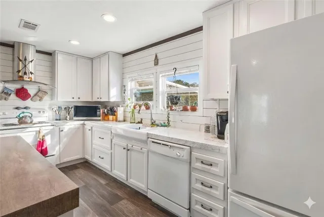 a kitchen with stainless steel appliances granite countertop a sink dishwasher a stove a dining table and chairs with wooden floor