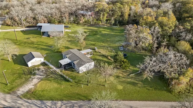 an aerial view of residential house with outdoor space and trees all around