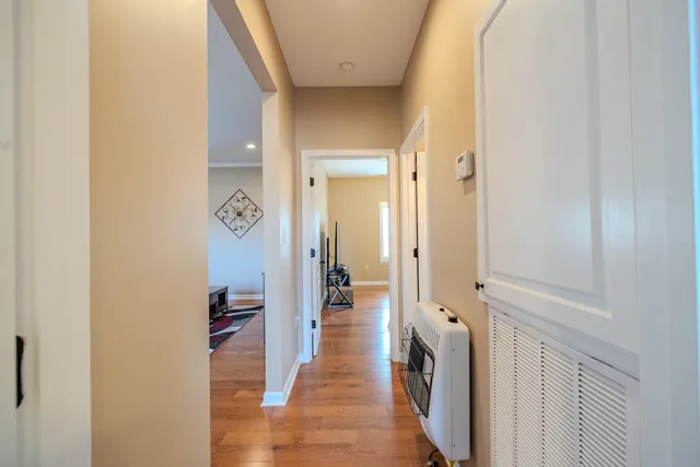 a view of a hallway with wooden floor and a bathroom