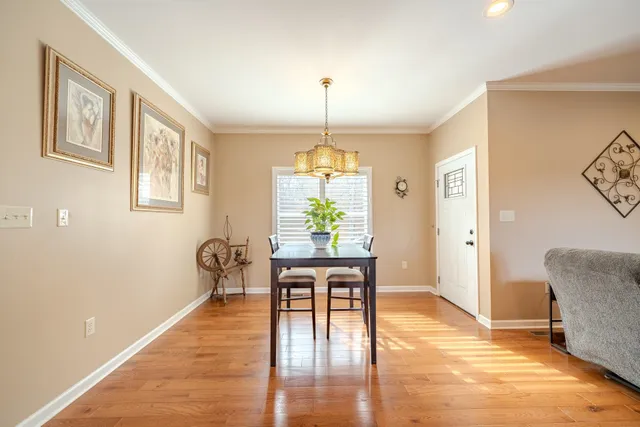 a dining room with wooden floor a chandelier a wooden table and chairs