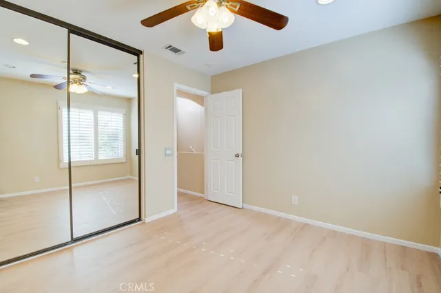 an empty room with closet and a chandelier fan