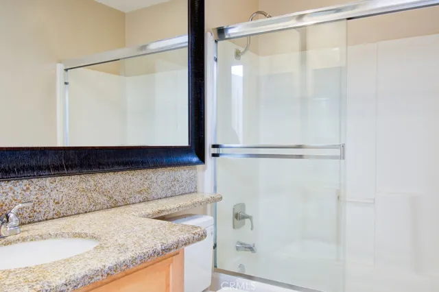 a bathroom with a granite countertop shower and a sink