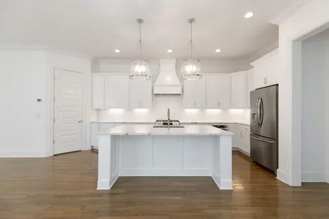 a kitchen with stainless steel appliances granite countertop a sink a refrigerator and a oven with wooden floor