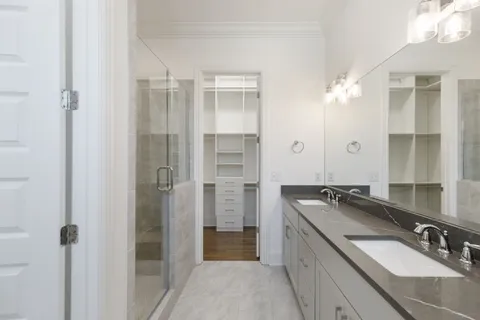 a bathroom with a granite countertop double vanity sink a mirror and a shower