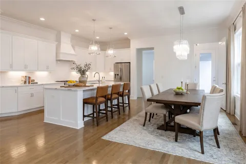a open dining room with kitchen island a dining table wooden floor and a sink