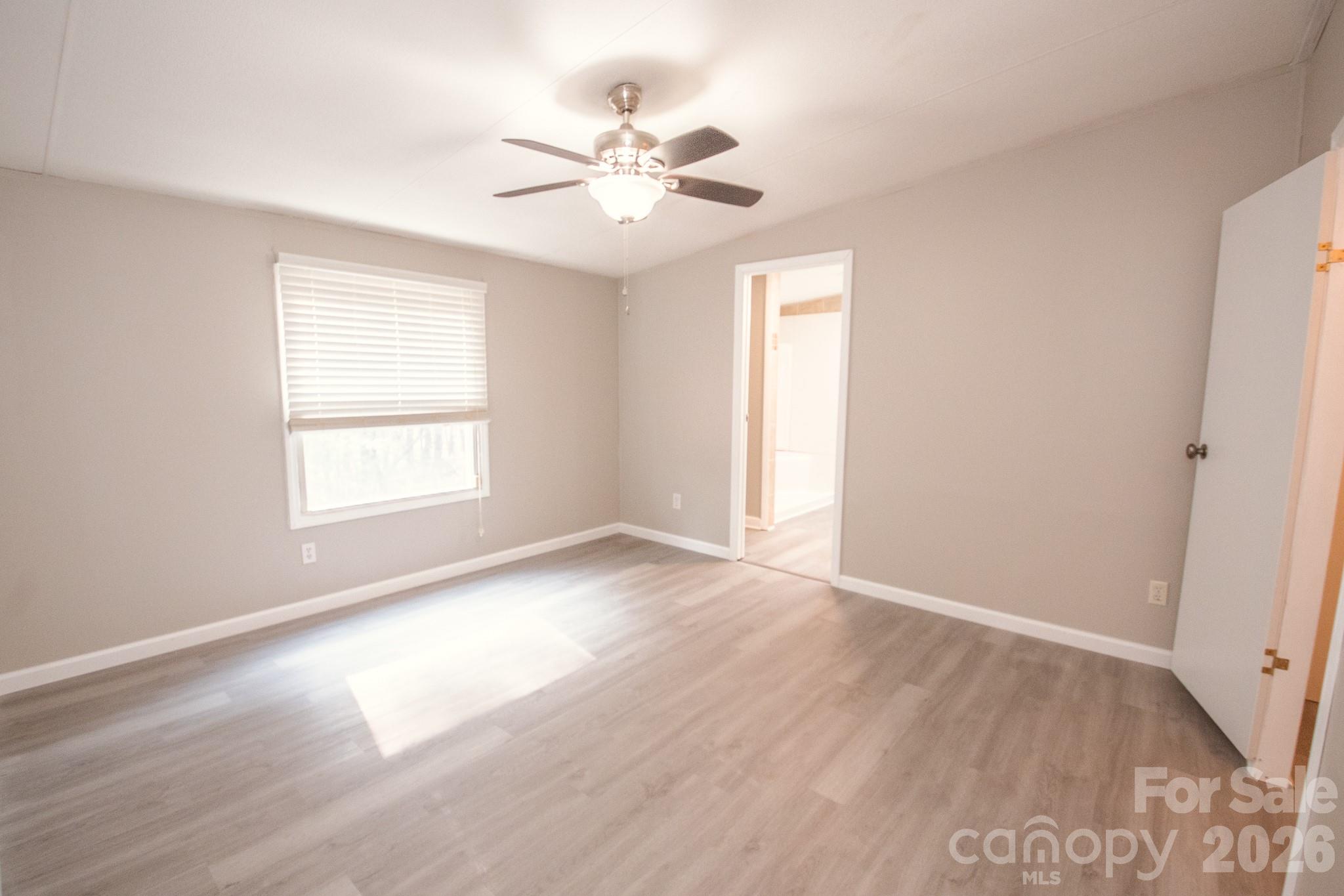 44082 Harper Hearne Road New London, NC 28127 - Photo 14 of 38 an empty room with wooden floor chandelier fan and windows