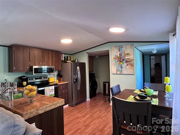 a kitchen with stainless steel appliances kitchen island granite countertop a refrigerator a stove a sink a dining table and chairs