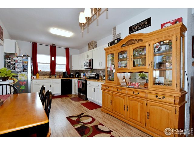 a kitchen with stainless steel appliances kitchen island granite countertop a refrigerator a stove a sink dishwasher and white cabinets with wooden floor