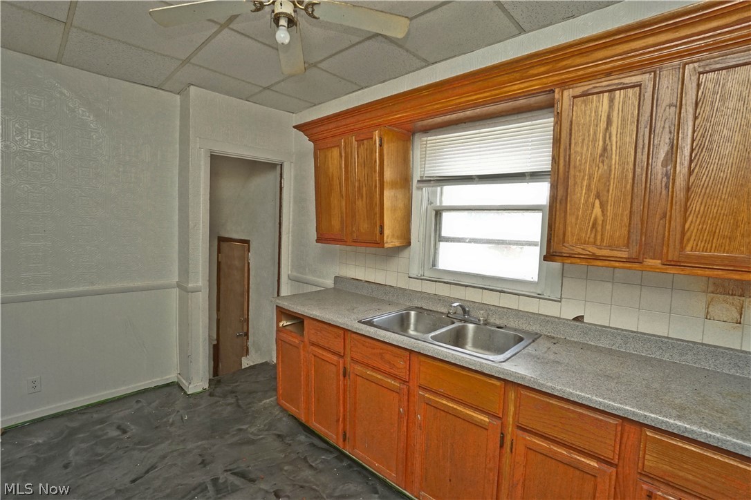 3443 Sheridan Road Youngstown, OH 44502 - Photo 7 of 24 Kitchen featuring wood cabinetry, a double basin stainless steel sink, and a tiled backsplash