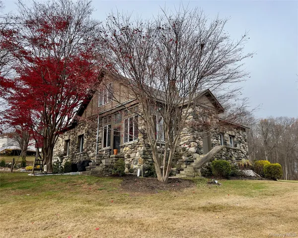 a view of a large white house with a large tree next to a yard