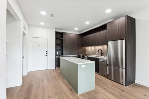 a kitchen with stainless steel appliances a refrigerator and a wooden floor