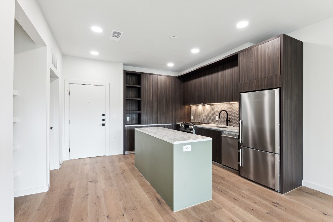 a kitchen with stainless steel appliances a refrigerator and a wooden floor