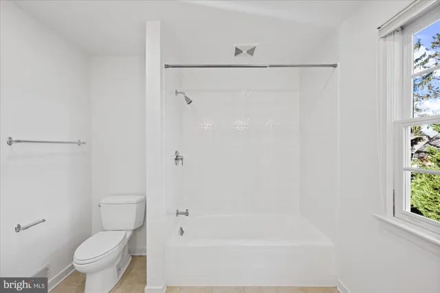 a view of an empty room with wooden floor and windows