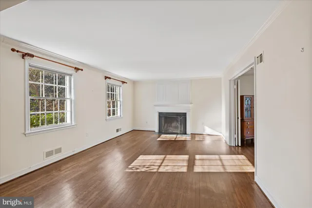 an empty room with windows and fireplace