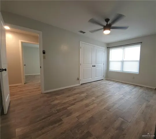 an empty room with wooden floor and windows