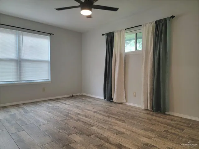 an empty room with wooden floor and windows