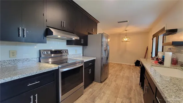 a kitchen with stainless steel appliances granite countertop a sink stove and refrigerator
