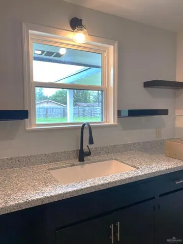a kitchen with granite countertop a sink window and cabinets