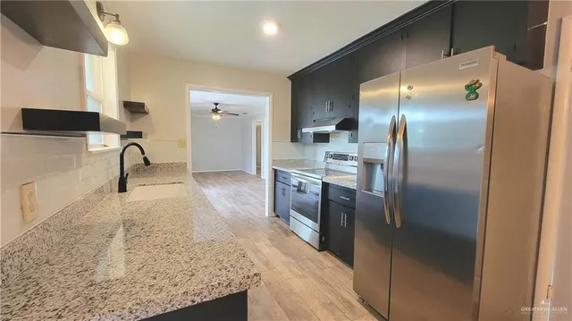 a kitchen with stainless steel appliances granite countertop a refrigerator a sink and a stove