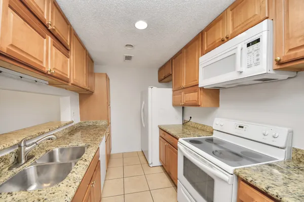 a kitchen with granite countertop a sink stove and cabinets