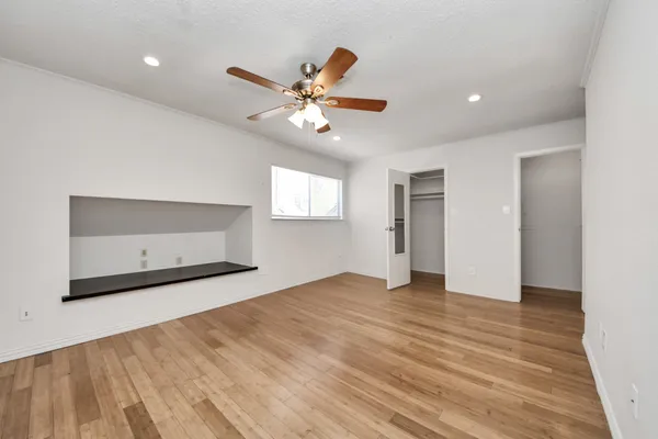 a view of an empty room with a window and a kitchen