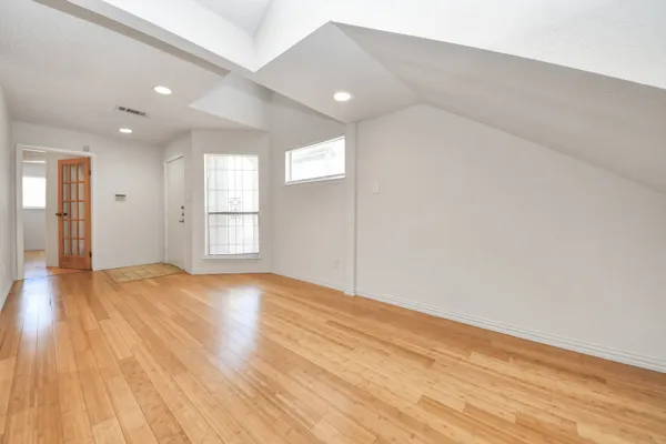 a view of empty room with wooden floor and fan