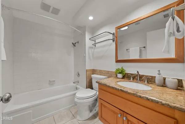 a bathroom with a granite countertop sink a toilet and bathtub