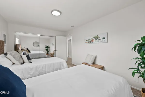 a bedroom with two beds and potted plant