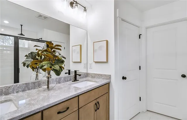 a bathroom with a granite countertop sink a mirror and shower