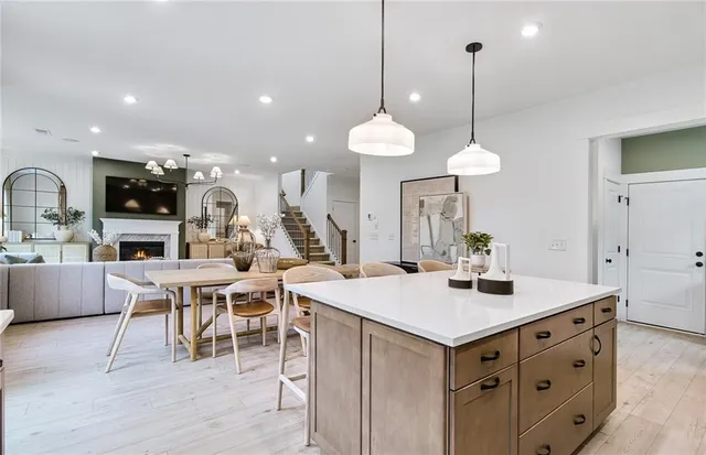 a living room with stainless steel appliances kitchen island a table chairs and a kitchen view