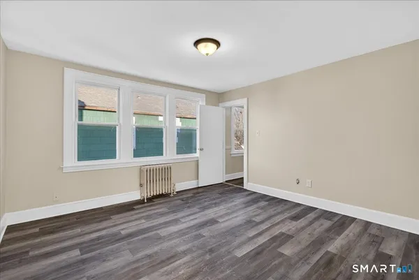 a view of an empty room with wooden floor and a window