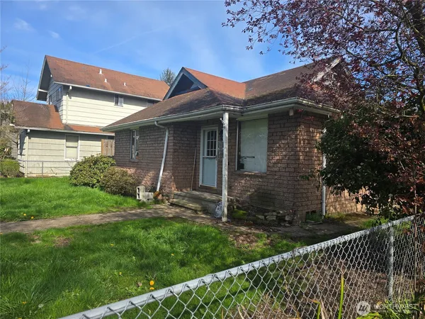 a view of a house with brick walls and a yard with a large tree
