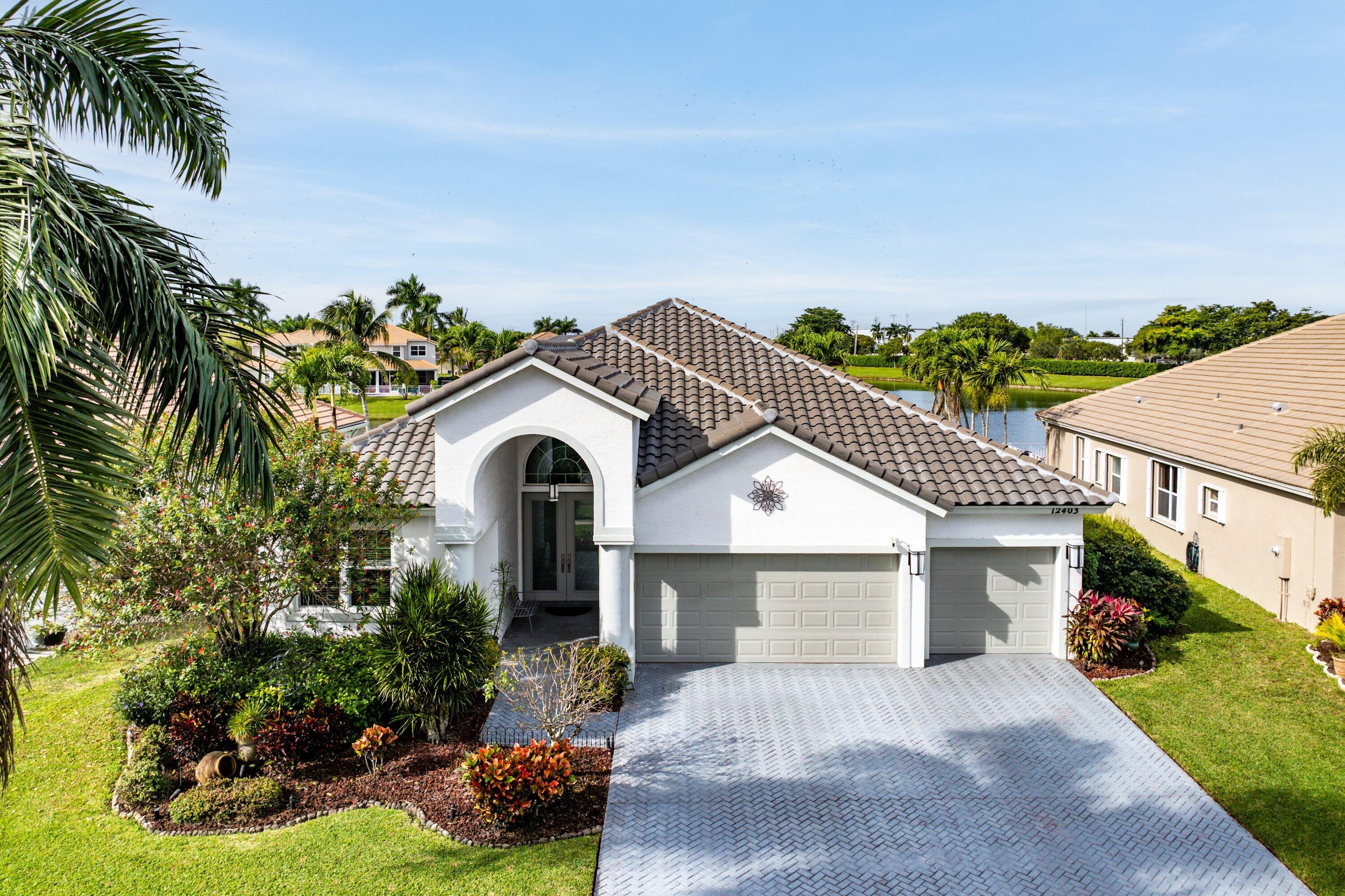 12403 Cascades Pointe Drive Boca Raton, FL 33428 - Photo 34 of 65 a front view of a house with a garden and plants