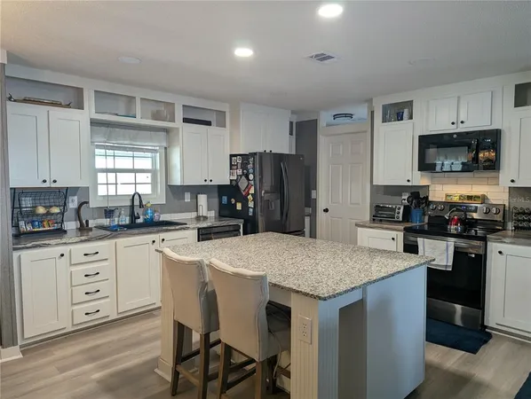 a kitchen with a counter top space a sink stainless steel appliances and cabinets