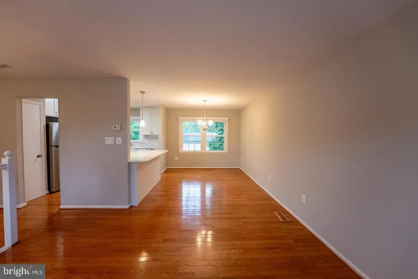 a view of a hallway with wooden floor and a kitchen