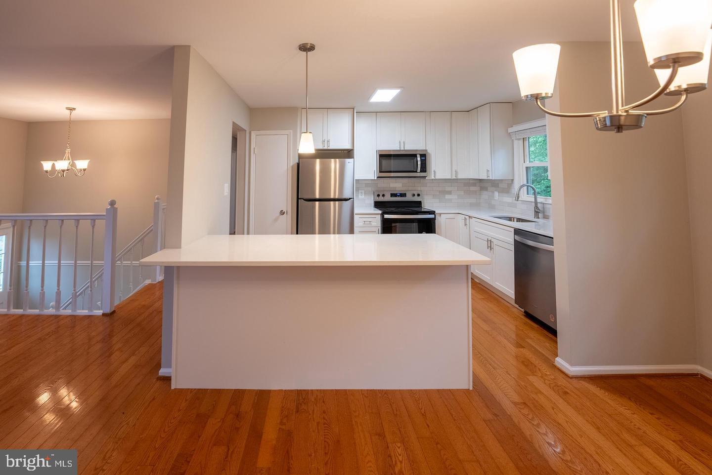 5629 Signal Point Court Burke, VA 22015 - Photo 10 of 48 a large kitchen with stainless steel appliances a large counter top a wooden floor a fireplace and a window