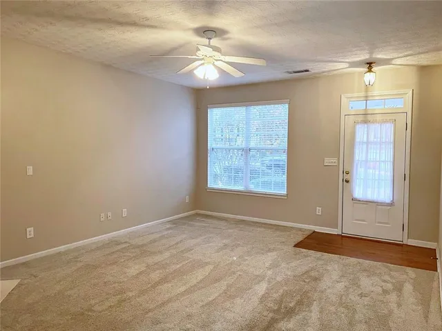 an empty room with windows and chandelier fan