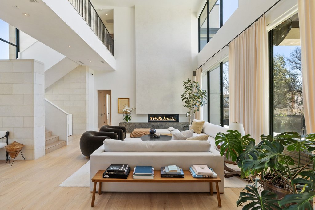 5 Inwood Cove Austin, TX 78746 - Photo 8 of 39 Living room featuring a warm lit fireplace, light wood-style flooring, and a high ceiling