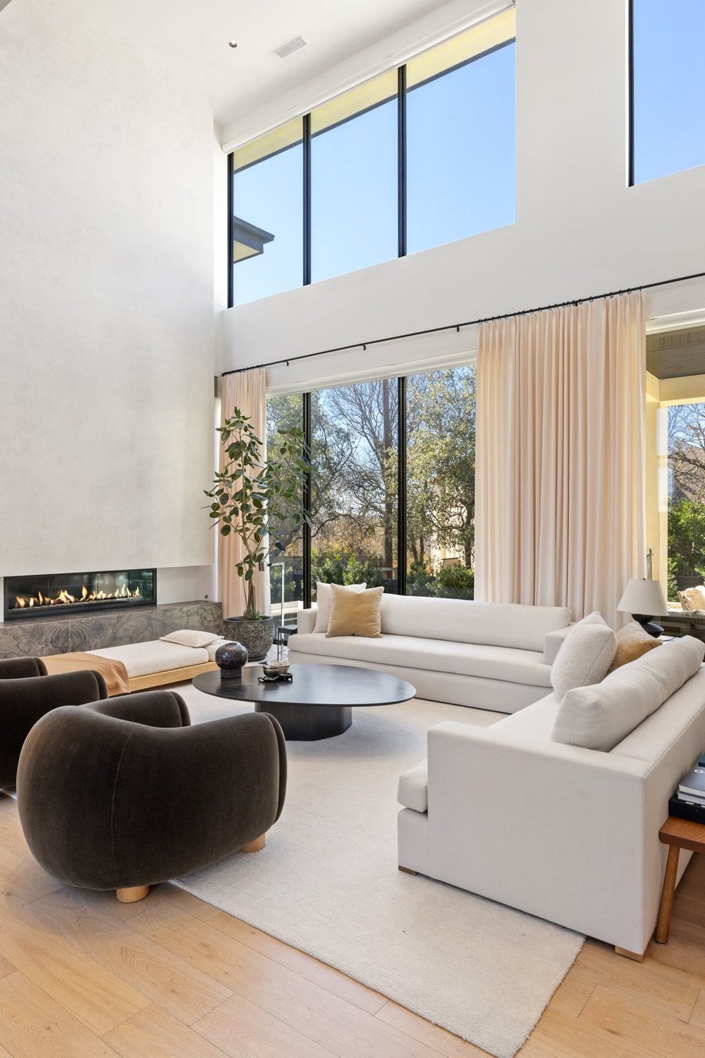 5 Inwood Cove Austin, TX 78746 - Photo 10 of 39 Living area featuring a high ceiling, light wood-type flooring, and a fireplace